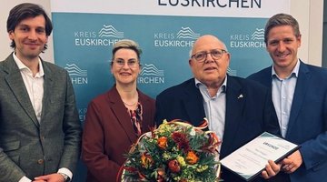 Auf dem Bild sieht man vier Personen; der zweite von rechts hält einen Blumenstrauß in der Hand"